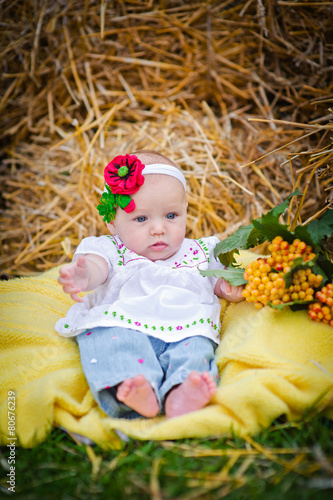 Beautiful little girl lying on a blanket in the hay