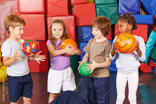 Kinder spielen mit B  llen in Turnhalle