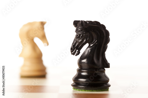 Confrontation - white and black chess knights standing 