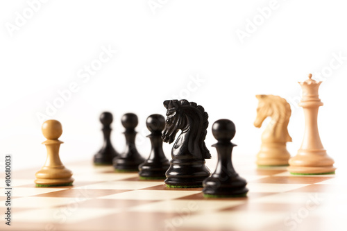 White pawn surrounded by black chess pieces on chessboard