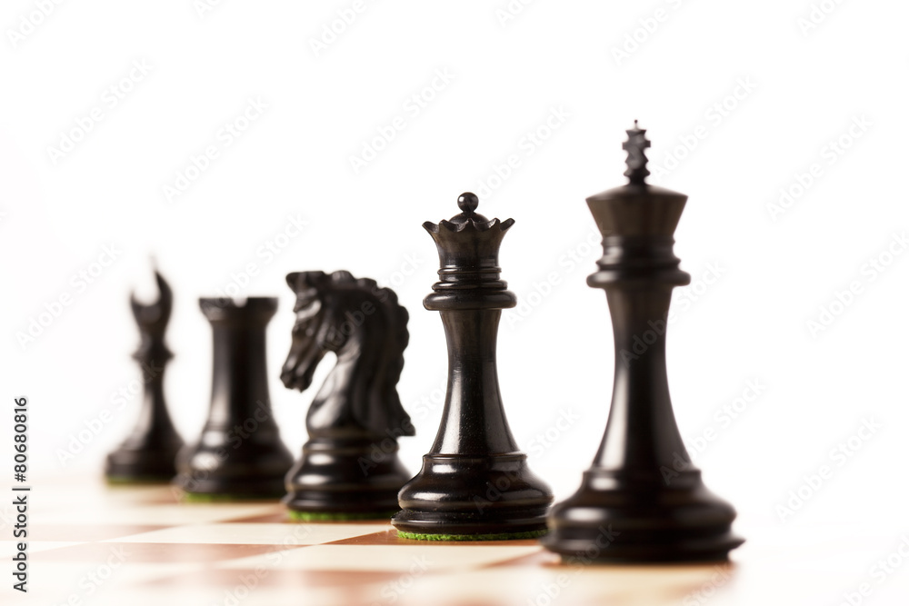 Black chess pieces on a chessboard standing in perspective Black chess pieces on a chessboard standing in perspective