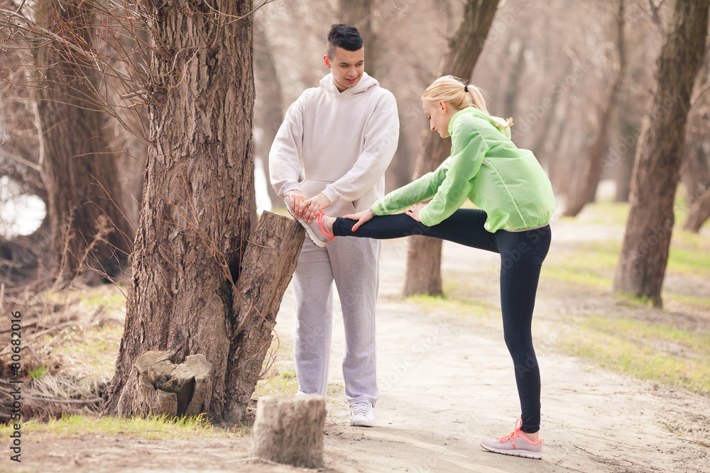 Obraz premium Young woman doing relaxation exercise with young man helping her