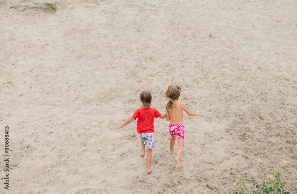 Fraternal twins running barefoot at the beach Fraternal twins running barefoot at the beach