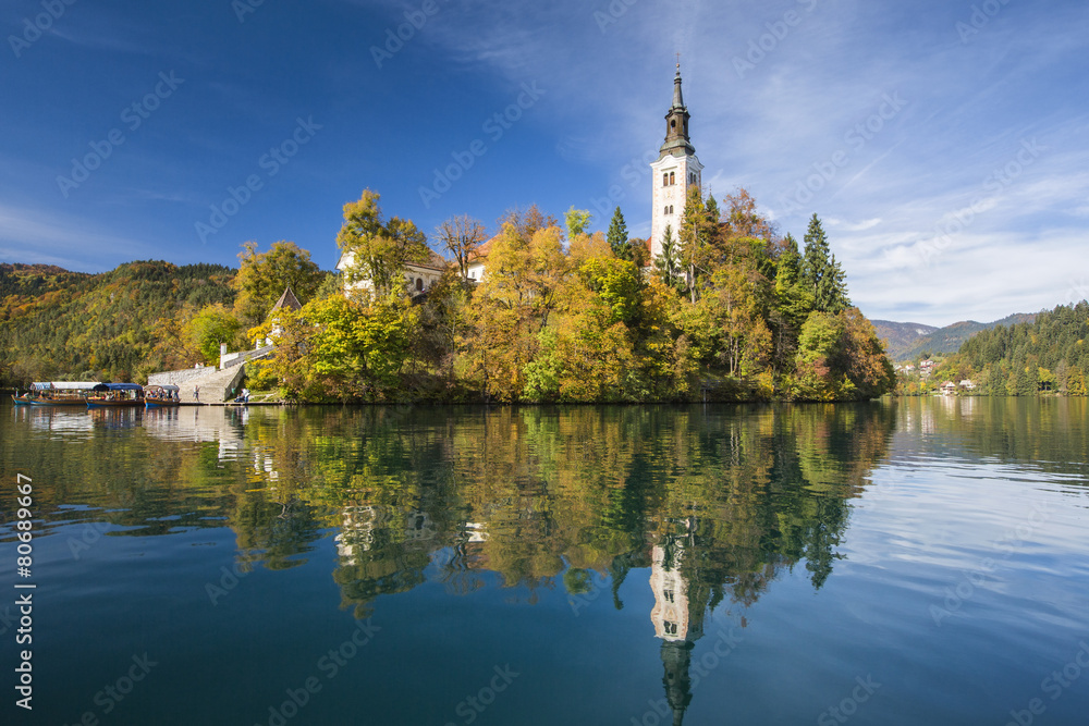 beflry and church in reflections on lake in Slovenia