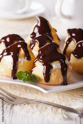 profiteroles with cream and chocolate glaze on a plate. vertical photo