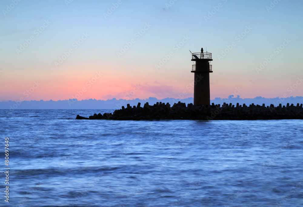 Stunning sunrise over sea with lighthouse