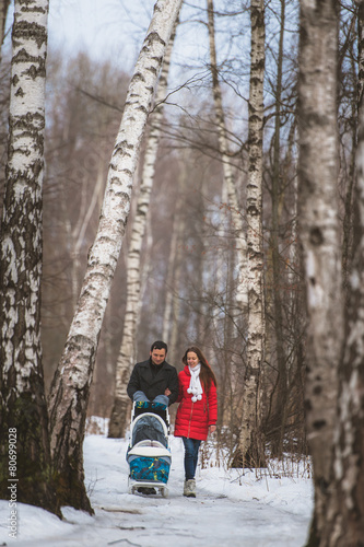 Young family walk in winter wood. Parent pulling sledge