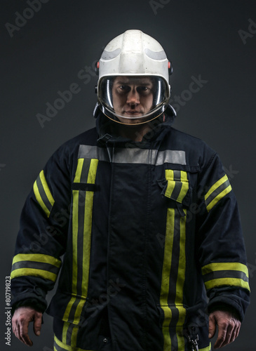 Firefighter in uniform on grey background © Fxquadro