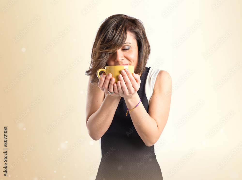 Pretty girl smelling a cup of coffee over white background