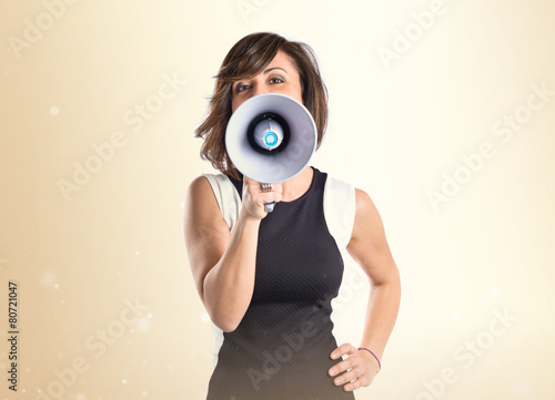 Pretty girl shouting with a megaphone over white background