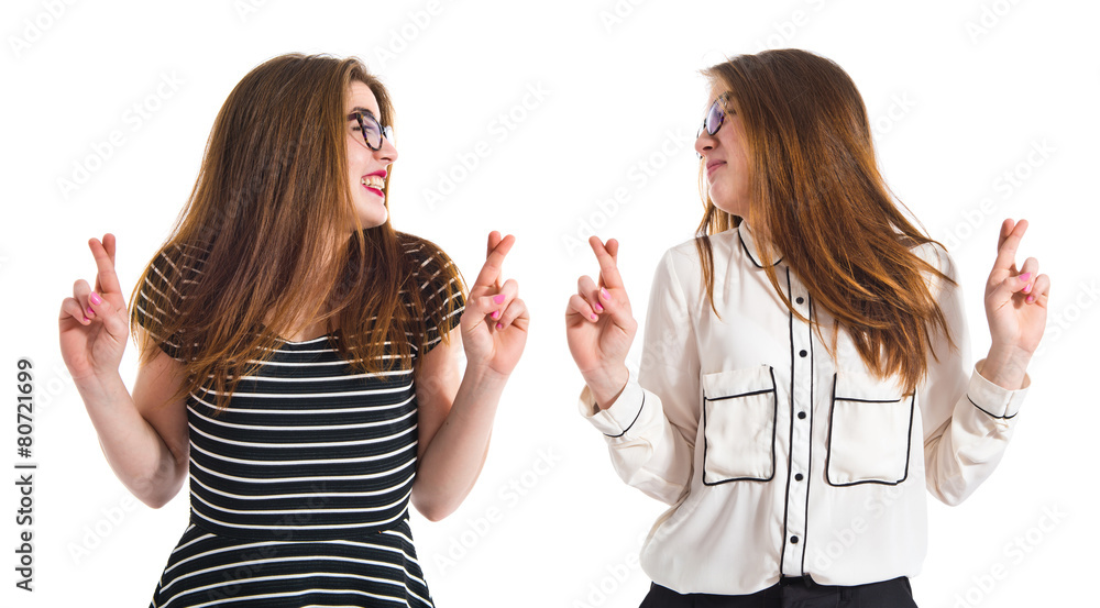 Twin girls with their fingers crossing Twin girls with their fingers crossing