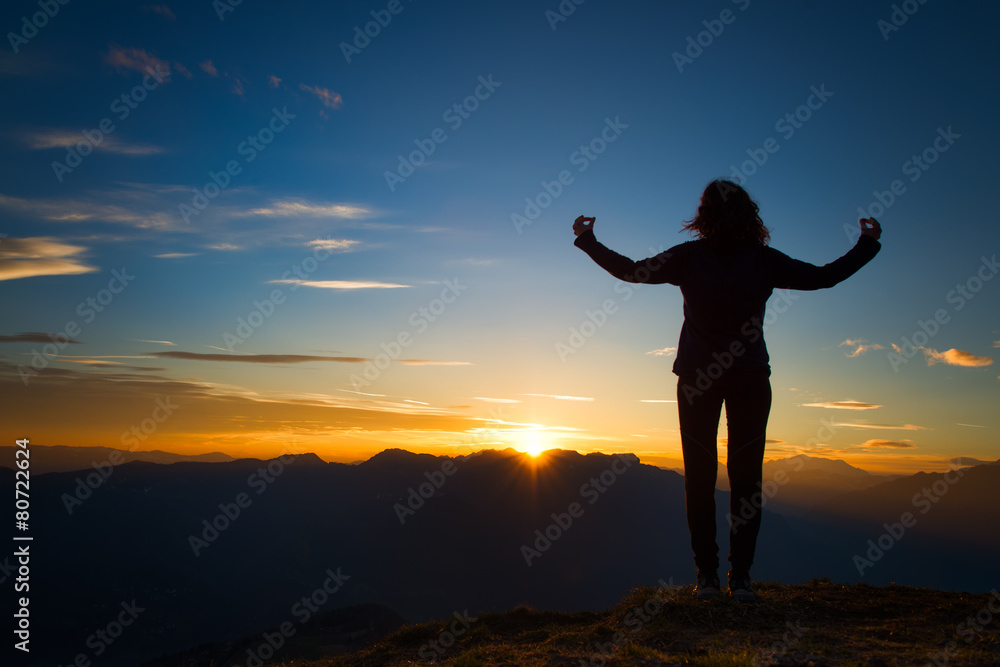 Fototapeta premium Girl in yoga meditation on top of a mountain at sunset