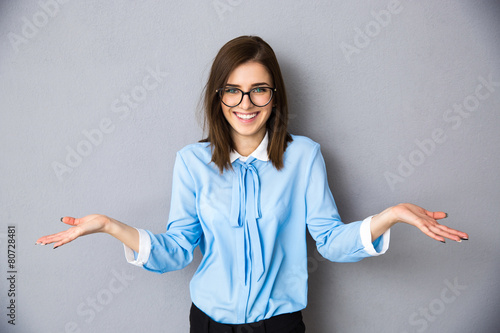 Smiling businesswoman in gesture of asking over gray background photo
