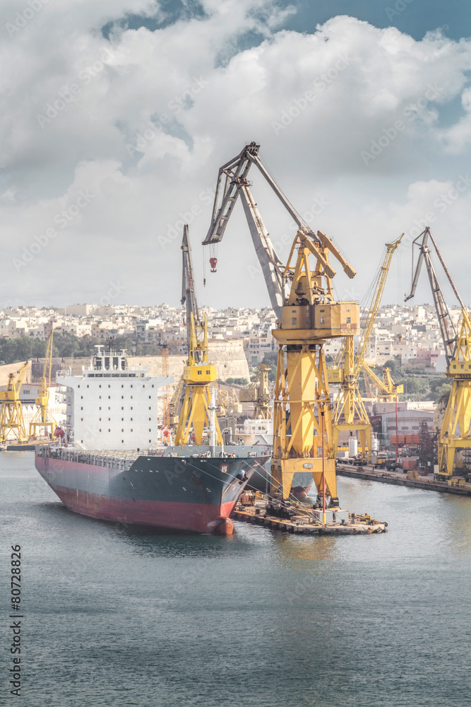 Fototapeta premium Cargo ship with crane in the harbor, Valletta, Malta