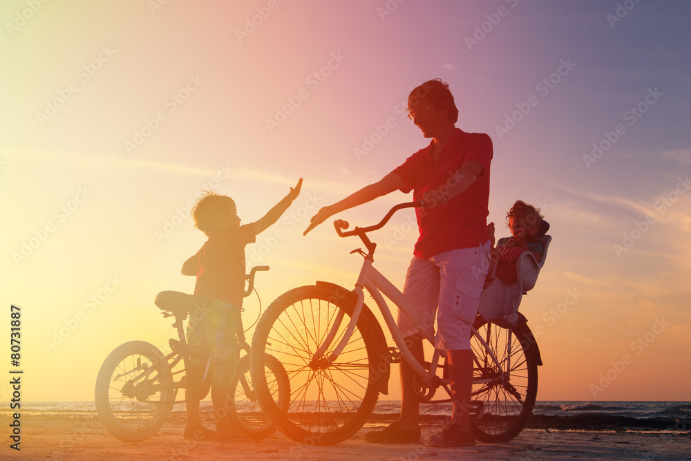 Fototapeta premium father with two kids on bikes at sunset