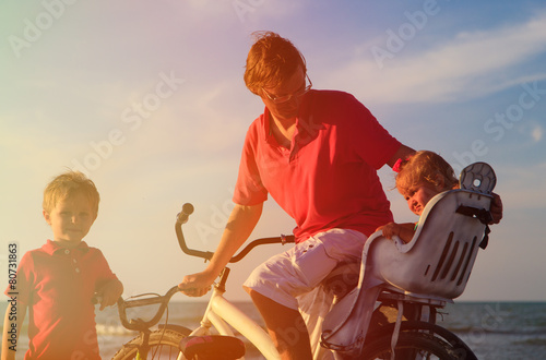 father with two kids biking at sunset sea © nadezhda1906