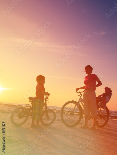 mother with kids biking at sunset