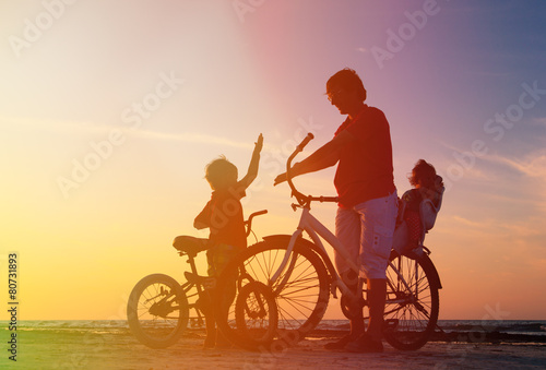 father with two kids on bikes at sunset