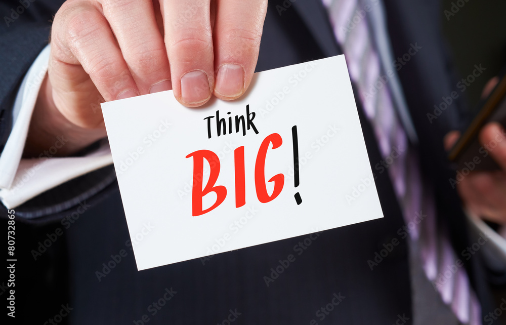 A businessman holding a business card with the words, Think Big A businessman holding a business card with the words, Think Big