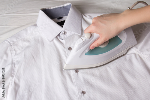 iron in female hand ironing cotton shirt