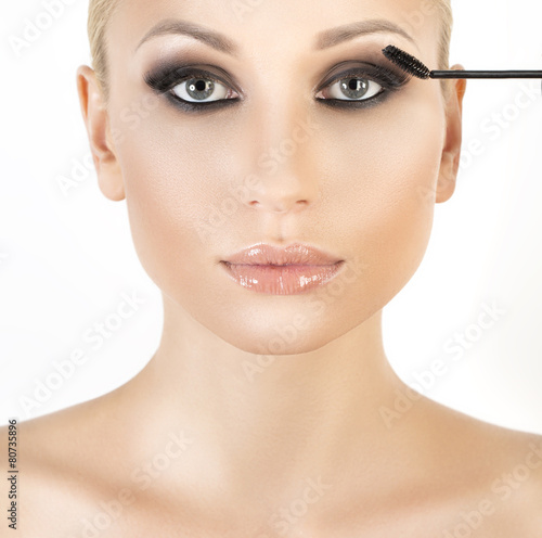 Woman applying mascara on her long eyelashes