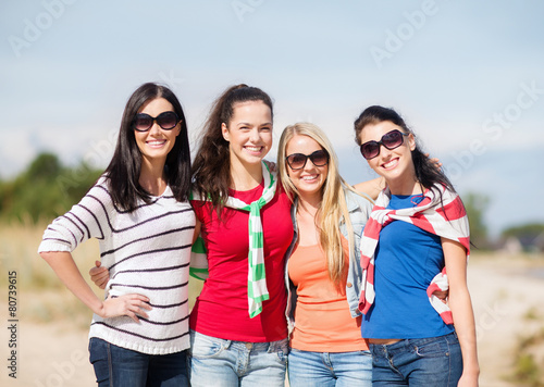 happy teenage girls or young women on beach © Syda Productions