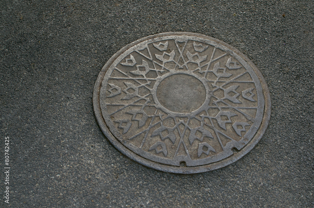 Metal circle of drain water on pavement