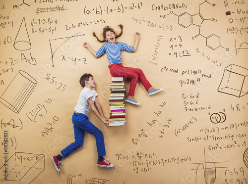 Cute boy and girl learning playfully in frot of a big blackboard photo