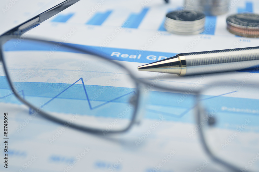 Pen and glasses on financial chart and graph Pen and glasses on financial chart and graph
