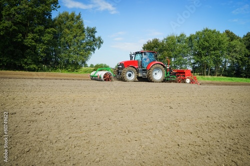 Roter Ackerschlepper mit Sämaschine von der Seite photo