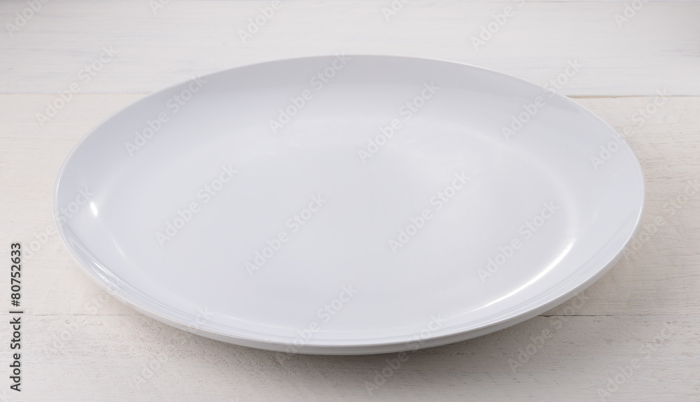 Empty white ceramic plate on wooden table