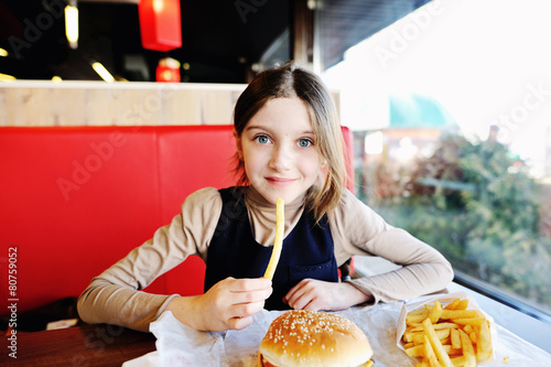Cute little  girl eating a hamburger