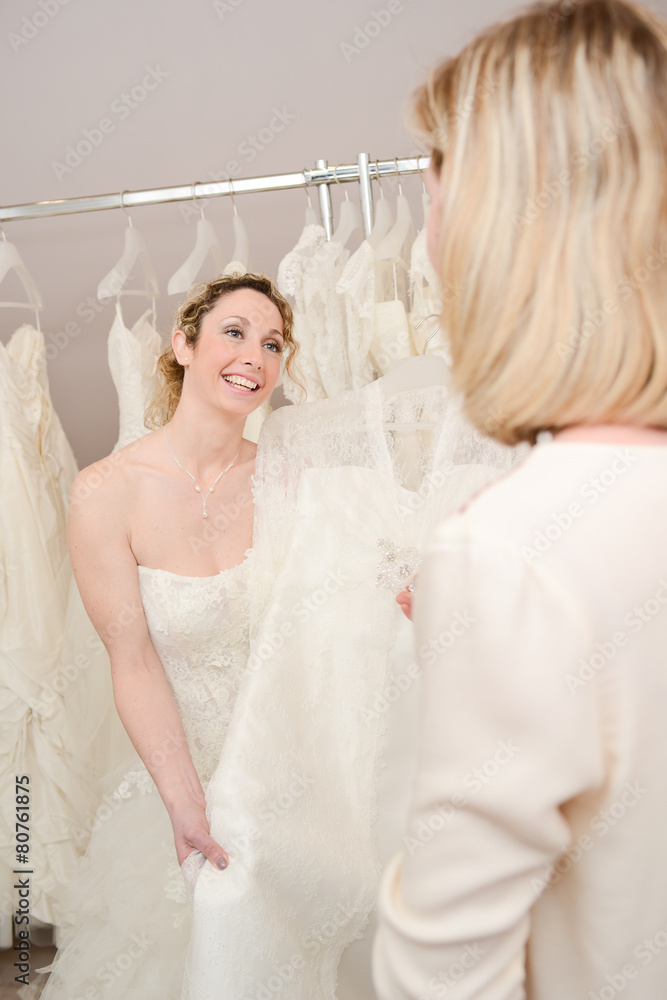 Beautiful young woman trying wedding dress in a bridal shop