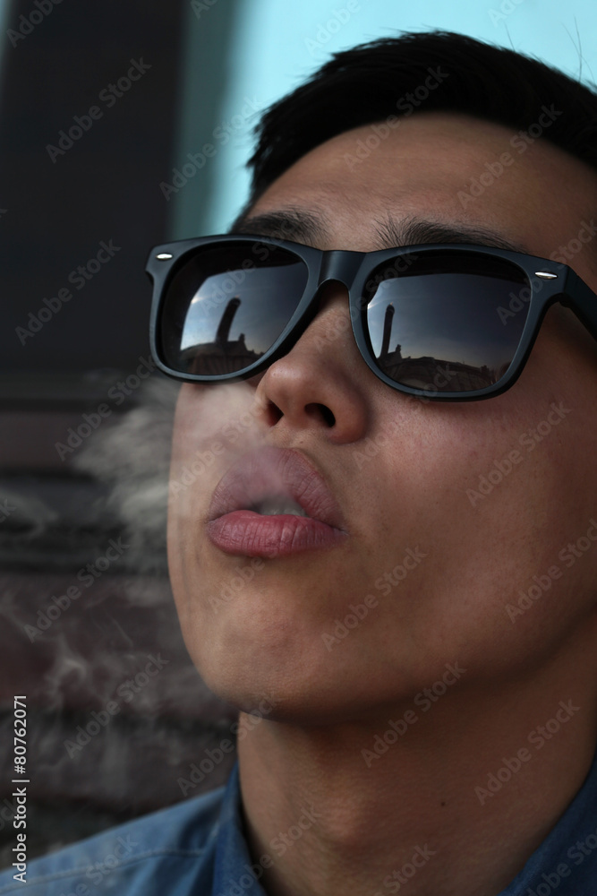Handsome young Asian man smoking and looking upward Handsome young Asian man smoking and looking upward