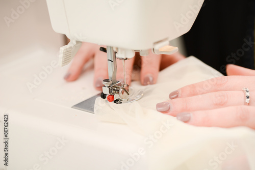 close up hands of young seamstress working on sewing machine