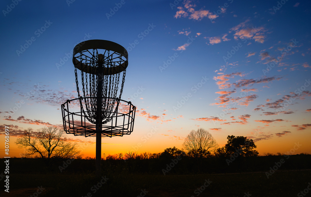 Naklejka premium Sylwetka kosza disc golfa w parku o zachodzie słońca