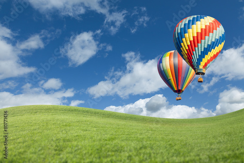 Hot Air Balloons In Beautiful Blue Sky Above Grass Field