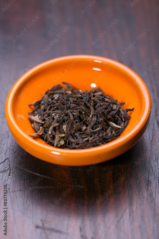 Bowl of dried green tea leaves on wooden background Bowl of dried green tea leaves on wooden background