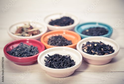assortment of dry tea in small bowl, on wooden background