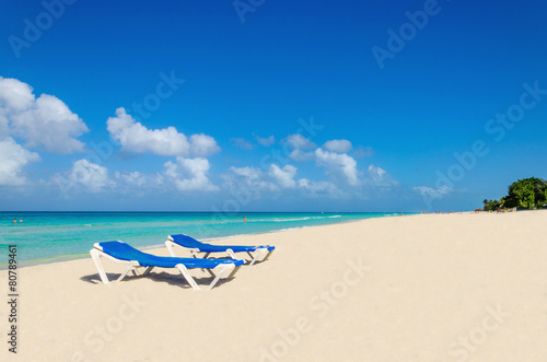 Blue sunbeds on sandy Caribbean beach against blue sky © A.Jedynak