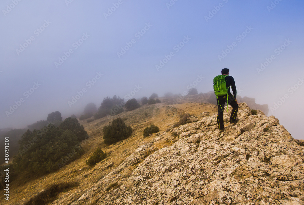 man walking on the edge of a cliff in foggy weather man walking on the edge of a cliff in foggy weather