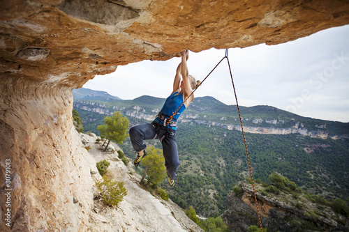 Woman rock climber struggling to make next movement up