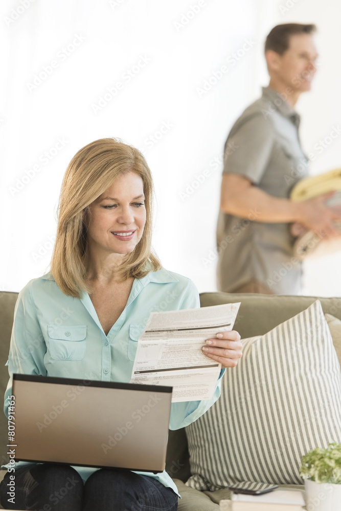 Mature Woman Paying Bills Using Laptop At Home Mature Woman Paying Bills Using Laptop At Home