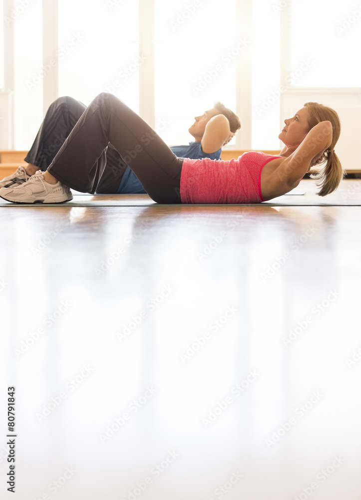 Side View Of Mature Couple Practicing Sit-Ups At Home Side View Of Mature Couple Practicing Sit-Ups At Home