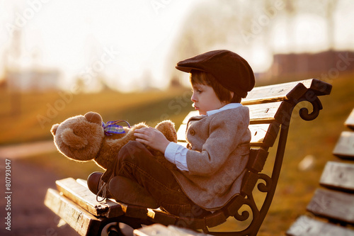Adorable little boy with his teddy bear friend in the park