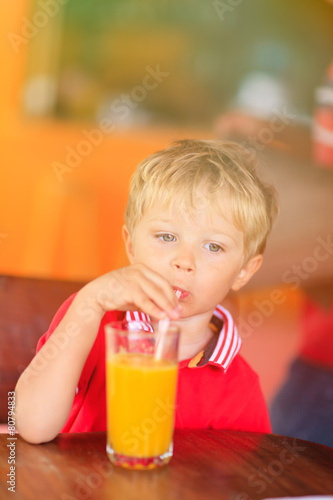 cute little boy drinking juice in cafe