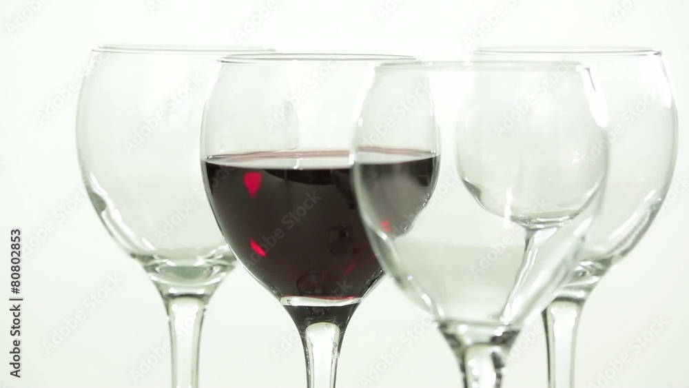 Pouring of red wine in a transparent glass on white Pouring of red wine in a transparent glass on white