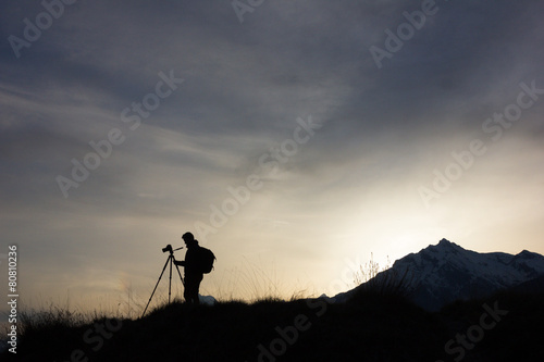 Silhouette of a professional photographer using tripod