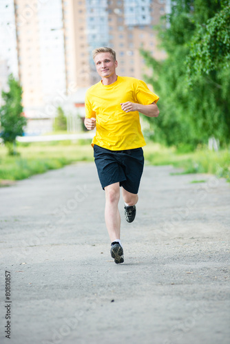 Sporty man jogging in city street park. Outdoor fitness.