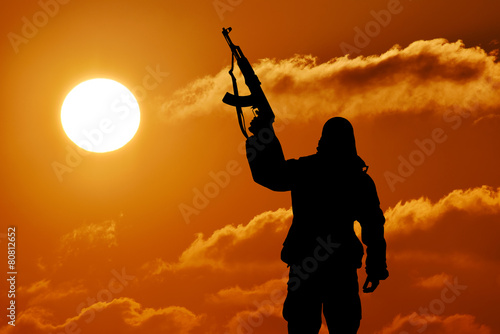 Silhouette of soldier officer with weapons at sunset